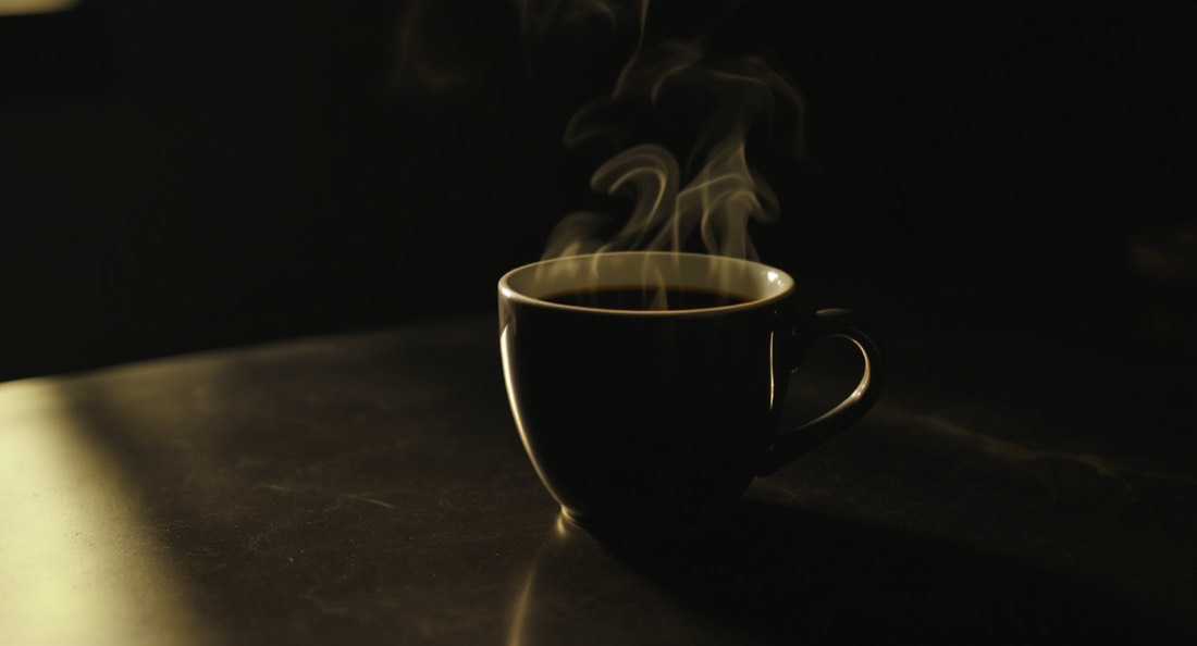 A black coffee in a plain ceramic cup with steam rising in morning light