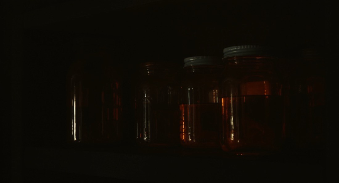 Plain unlabelled amber glass jars on a dark wooden shelf